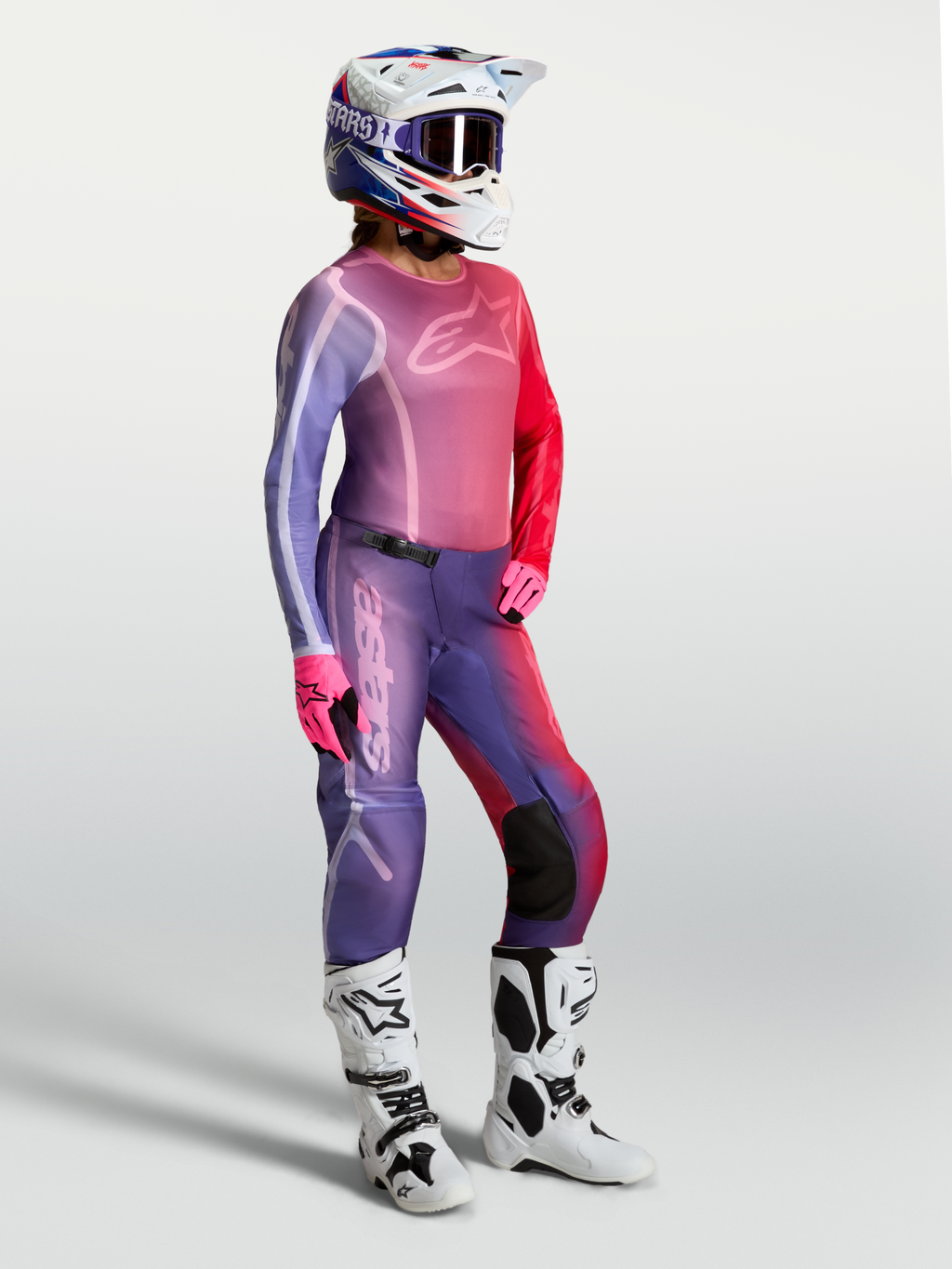 Alpinestars Camisola Stella Fluid Kepler, camisola de motocross para mulher, roxa e vermelha, com calças e botas brancas.