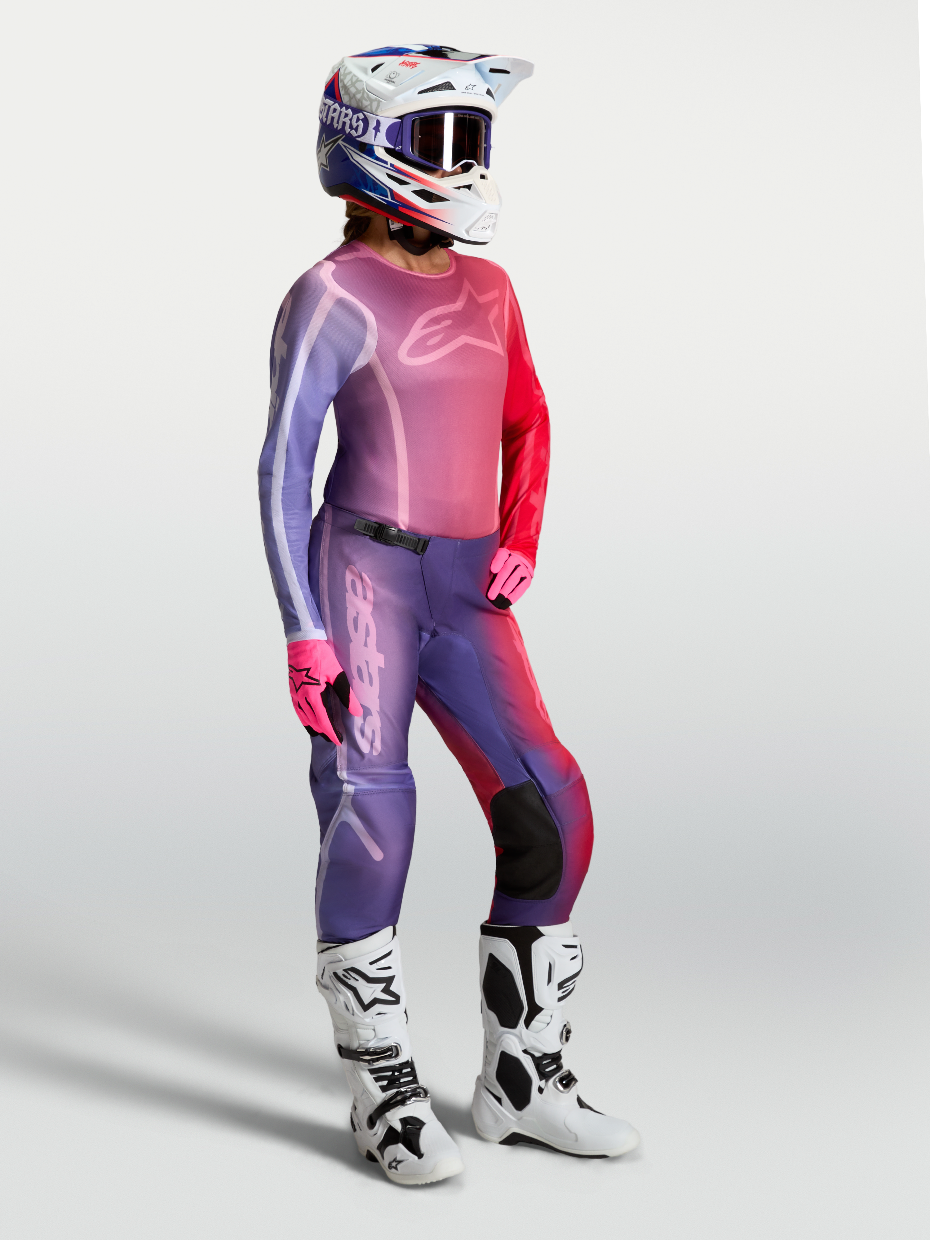 Alpinestars Camisola Stella Fluid Kepler, camisola de motocross para mulher, roxa e vermelha, com calças e botas brancas.