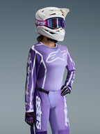 Conjunto de Equipamento Alpinestars Stella Fluid Apex Feminino 2026, camisola e calças de motocross em roxo e lavanda, usado por uma piloto com capacete branco e óculos roxos, apresentando logótipos Alpinestars brancos em destaque