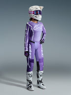 Conjunto de Equipamento Alpinestars Stella Fluid Apex 2026, roxo e lavanda, piloto feminina de motocross a usar camisola e calças a condizer, capacete branco com óculos de proteção roxos, botas brancas e pretas, luvas pretas e roxas, equipamento completo de alta performance para competição todo-o-terreno feminina
