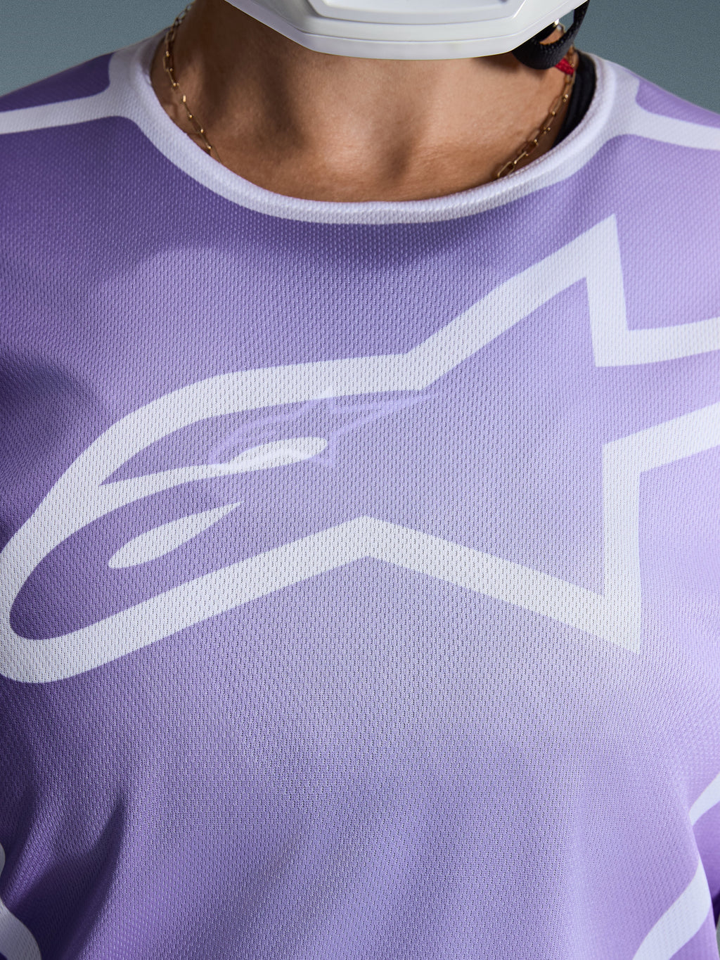 Alpinestars Stella Fluid Apex Jersey 2026, pormenor do peito, roxa com grafismos brancos, com um grande logótipo Astars branco em construção de malha de poliéster