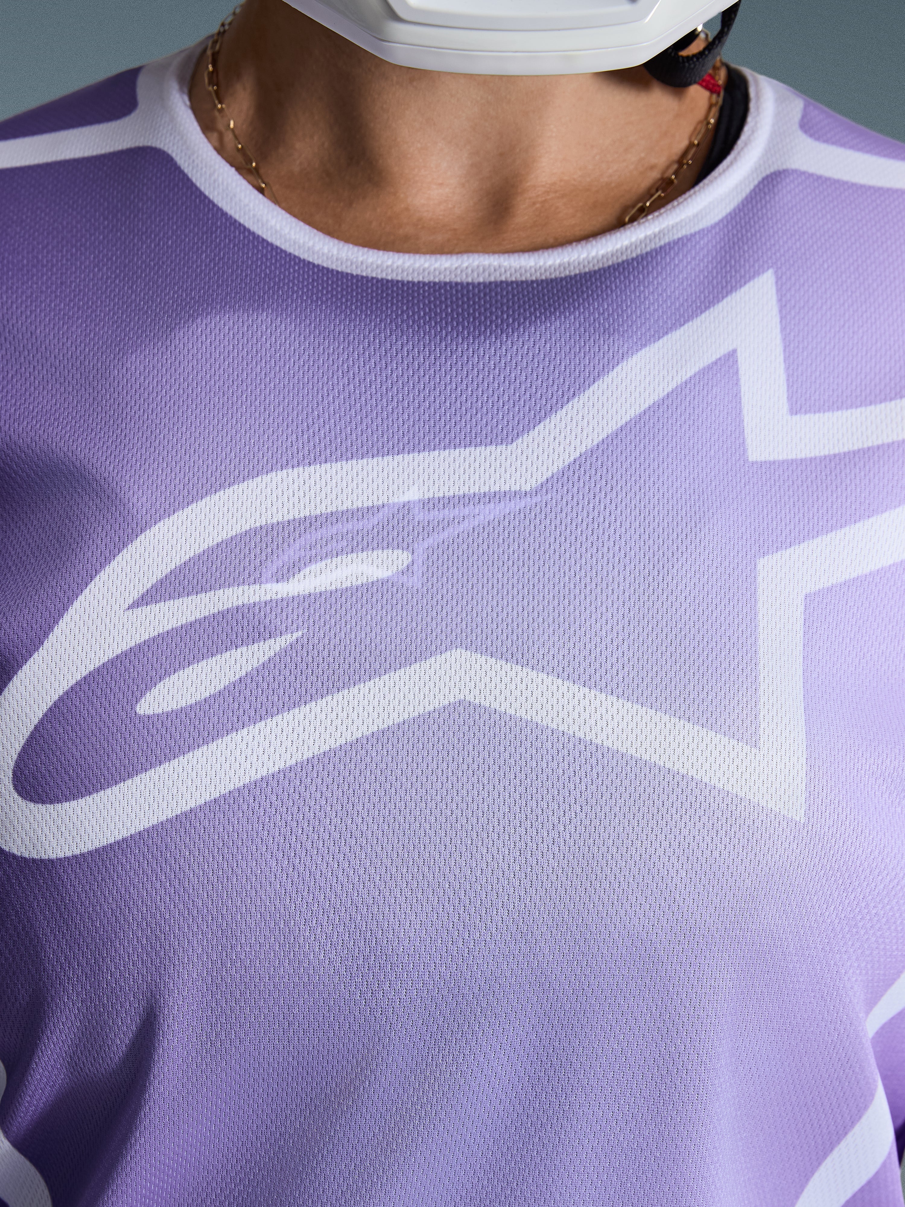 Alpinestars Stella Fluid Apex Jersey 2026, pormenor do peito, roxa com grafismos brancos, com um grande logótipo Astars branco em construção de malha de poliéster