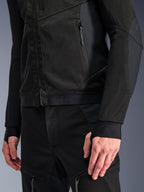 Casaco Alpinestars Troop-Air Pro em Black Black, grande plano de casaco de ar técnico blindado com construção detalhada em malha técnica 2D, bolsos com fecho de correr e bainha elástica com a marca Alpinestars, mangas com passadores para os polegares integrados, combinado com equipamento de motociclismo a condizer.