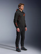 Alpinestars Chrome Air Sport Hoodie, Preto Vermelho Fluo, casaco de condução urbana com tech fleece, usado com calças pretas e botas de motociclismo, apresentando painéis de ventilação em malha e logótipos em vermelho fluorescente no peito e na manga.