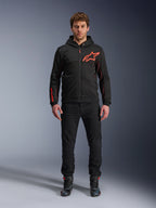 Alpinestars Chrome Air Sport Hoodie, preto e vermelho fluo, casaco de motociclismo urbano com construção em tech fleece, com um grande logótipo Astars vermelho no peito e marca na manga, vestido por um modelo com calças pretas e sapatos de condução
