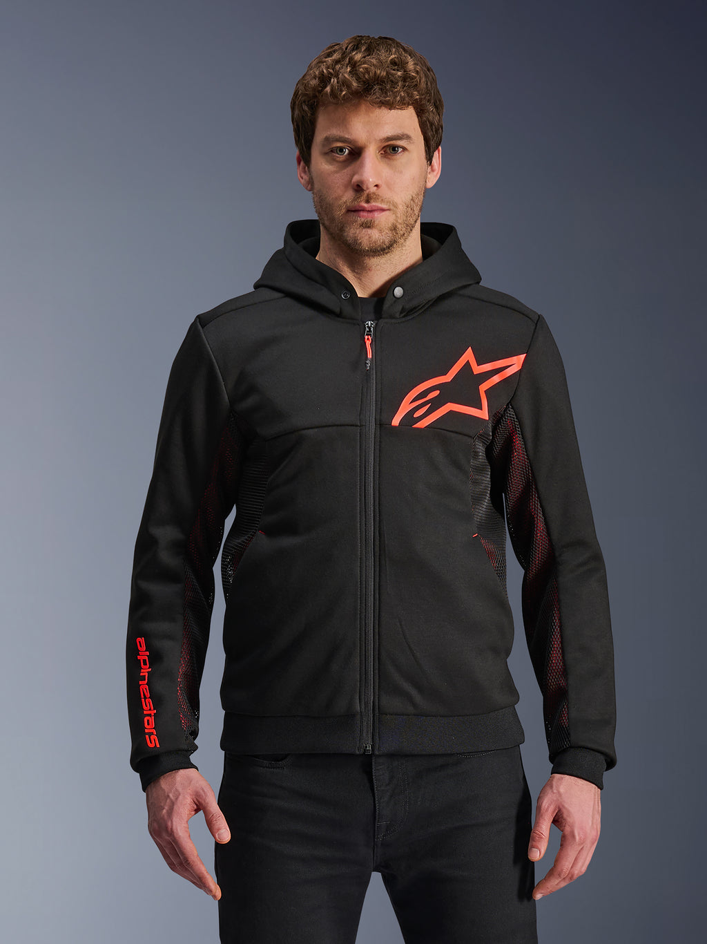 Alpinestars Chrome Air Sport Hoodie, hoodie preto com fecho de correr com logótipo de estrela em vermelho fluo e detalhes nas mangas, painéis laterais em malha vermelha para ventilação, equipamento de condução urbana casual usado por um modelo