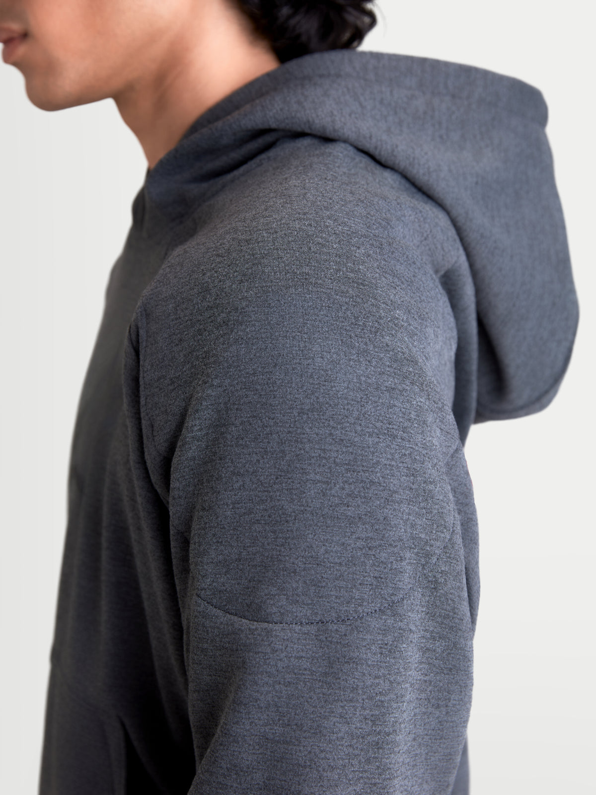 Alpinestars Ageless Hoodie, casaco de moto urbano para homem em cinzento melange de asfalto, vista lateral em close-up a mostrar a construção em tecido de malha e os detalhes de reforço nos ombros num modelo