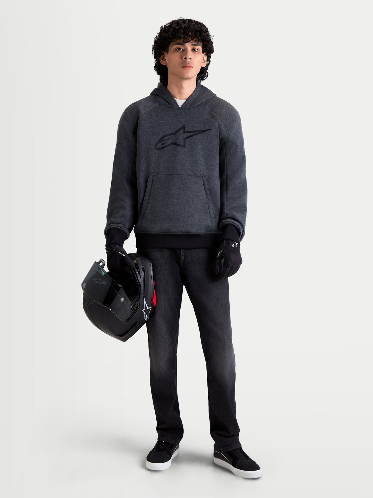 Alpinestars Ageless Hoodie, blusão de moto urbano para homem em cinzento melange de asfalto, vista frontal num modelo a usar luvas de moto pretas e a segurar um capacete, com proteção integrada nos ombros e cotovelos