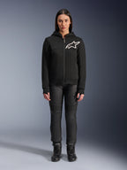 Mulher a usar o Alpinestars Stella Chrome V2 Sport Hoodie, preto com logótipo Astars branco no peito, combinado com calças técnicas de condução pretas e botas, design de vestuário urbano para motociclismo