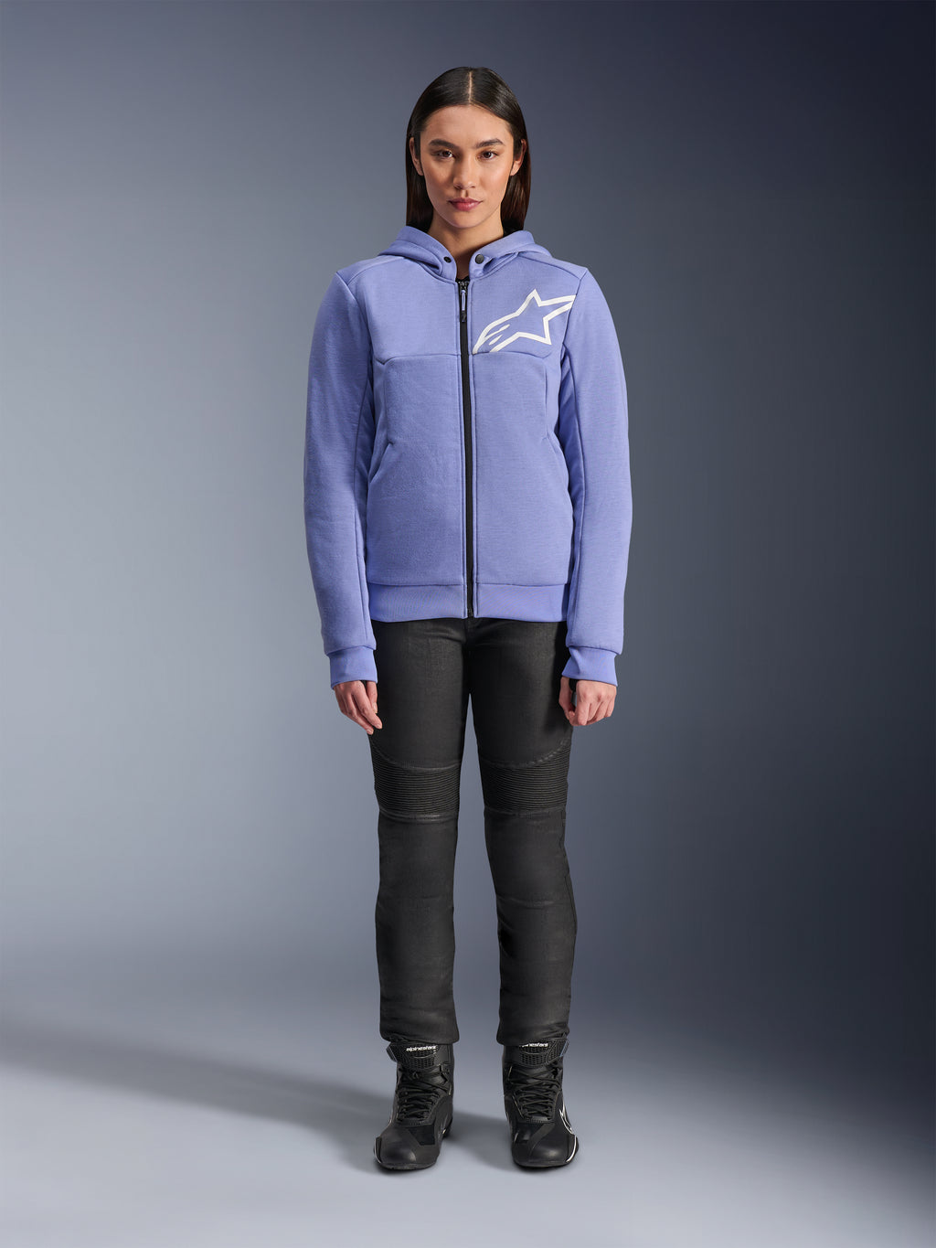 Alpinestars Stella Chrome V2 Sport Hoodie para Mulher, azul violeta com logótipo Astars branco no peito, hoodie técnico com fecho integral e capuz, usado com calças de motociclismo pretas e botas de condução, equipamento de condução urbana casual para mulher