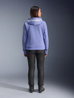 Alpinestars Stella Chrome V2 Sport Hoodie, azul violeta, vista traseira de uma mulher a usar o hoodie com o logótipo Alpinestars branco no capuz, calças pretas e botas de motociclismo, vestuário urbano casual para motociclismo