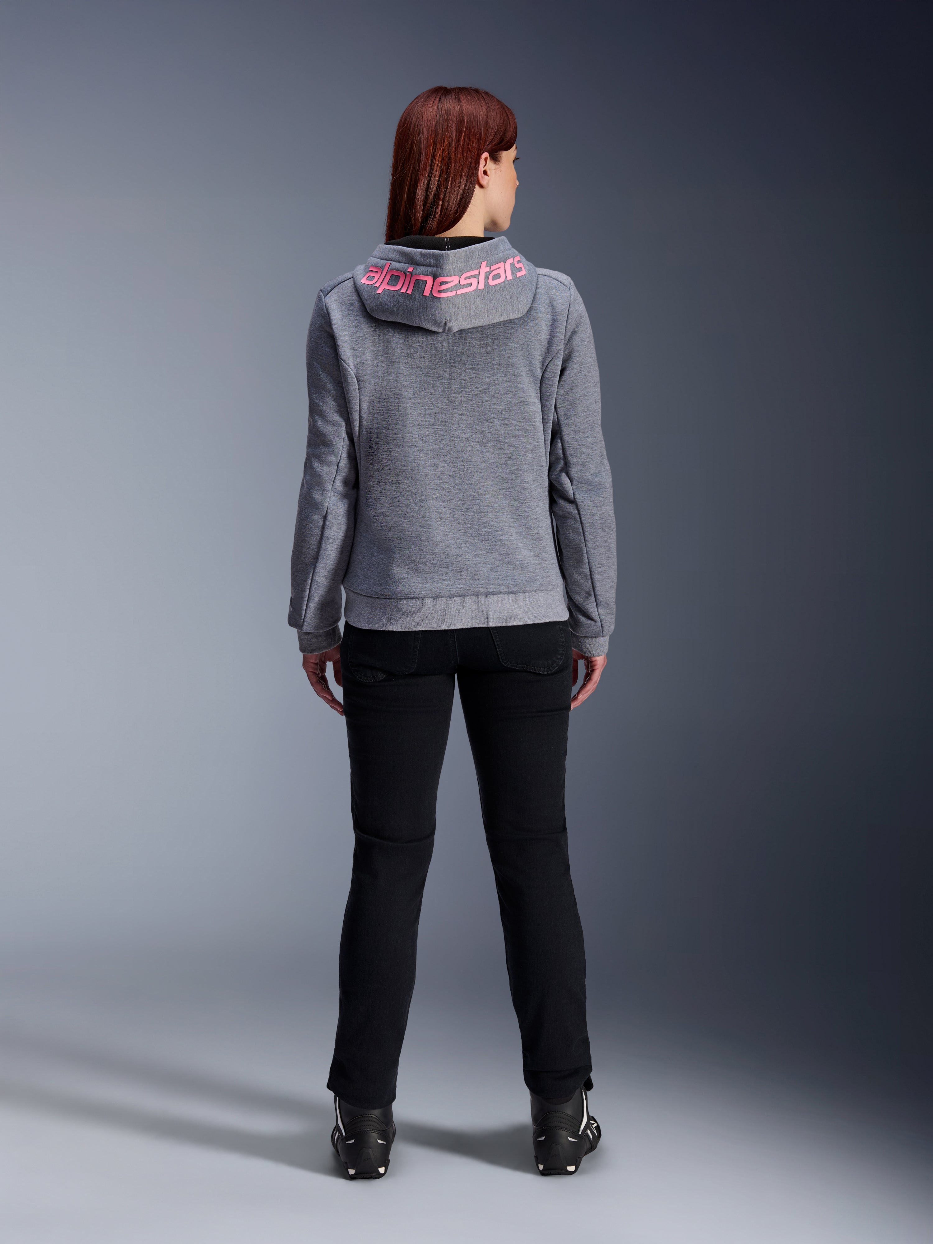 Alpinestars Stella Chrome V2 Sport Hoodie, Women's Motorcycle Hoodie, Gray Heather and Pink Fluo, back view showing pink Alpinestars logo on the hood, worn with black riding pants and boots, casual motorcycle apparel for women
