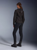 Alpinestars Stella Radium Tech Hoodie, Women's Black Urban Riding Hoodie, rear view showing 'ALPIN' branding on the hood, paired with black technical riding pants and black boots, lightweight windproof tech shell.