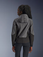 Woman wearing Alpinestars Stella Radium Tech Hoodie, rear view, Deep Gray Black, two-tone gray and black 3-layer windproof shell, Alpinestars branding on the hood, athletic fit urban motorcycle apparel