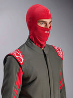 Alpinestars ZX Evo V3 Balaclava, Vermelha, usada por um piloto num fato de corrida cinzento com detalhes em vermelho e branco, apresentando um logótipo Astars branco na testa e uma abertura para tubo de hidratação, camada de base resistente às chamas para automobilismo