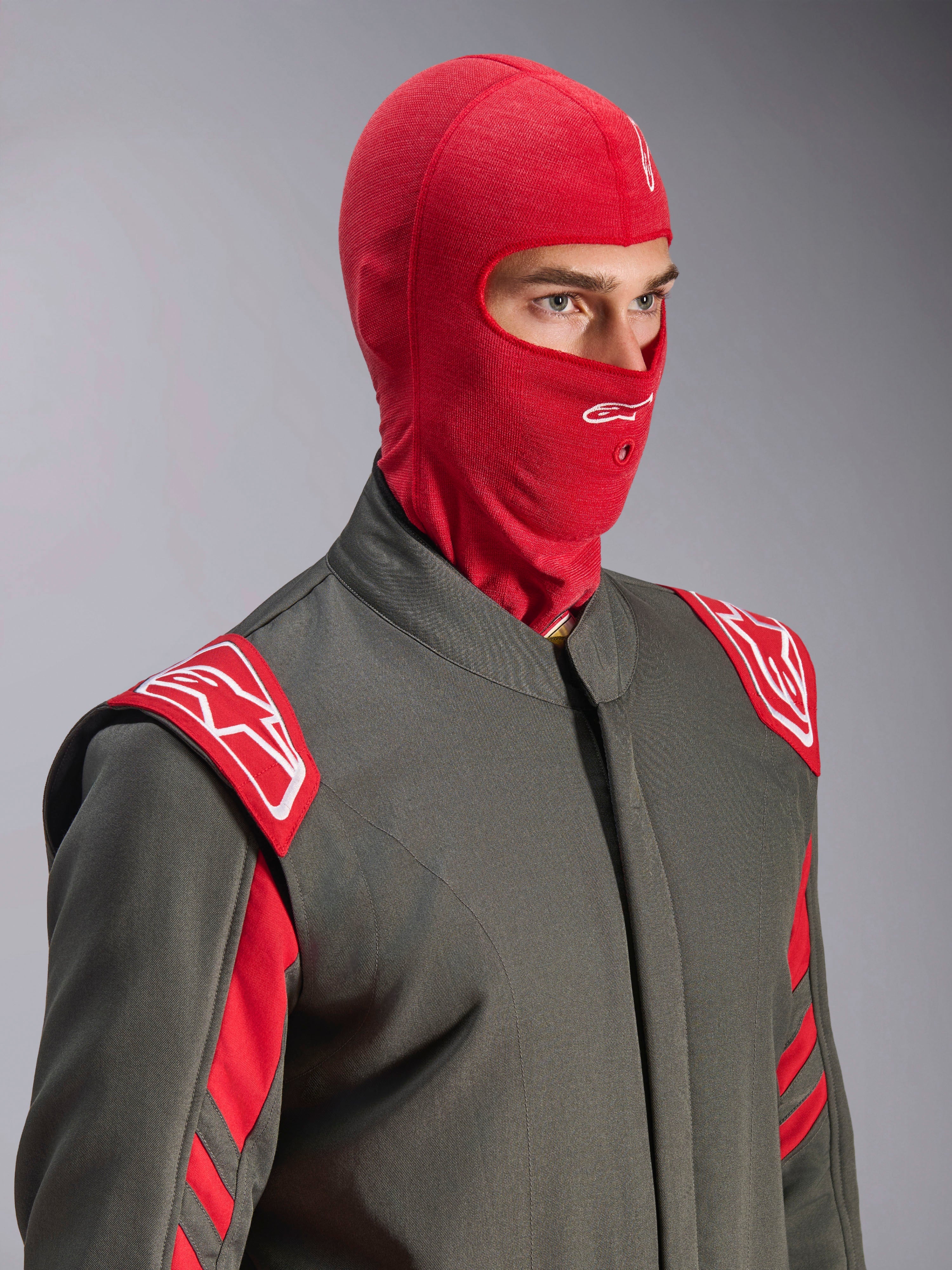 Alpinestars ZX Evo V3 Balaclava, Vermelha, usada por um piloto num fato de corrida cinzento com detalhes em vermelho e branco, apresentando um logótipo Astars branco na testa e uma abertura para tubo de hidratação, camada de base resistente às chamas para automobilismo