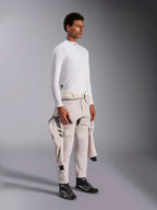Alpinestars ZX Evo V3 Long Sleeve Top, camada interior de automobilismo branca resistente a chamas, vestida por um modelo com um fato de corrida atado à cintura, camada técnica leve com gola alta e detalhe do logótipo.