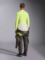 Alpinestars ZX Evo V3 Top de Manga Comprida, Amarelo Fluo, vista traseira de modelo a usar camada de base resistente ao fogo com calças de fato de corrida escuras e botas, roupa interior técnica profissional para desportos motorizados