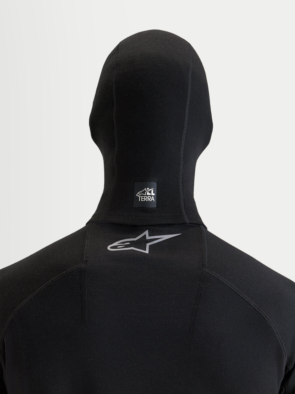 Alpinestars AT-8 Merino Balaclava, balaclava de moto preta, vista traseira mostrando a etiqueta All Terra no pescoço e o logótipo Astar refletivo na parte superior das costas