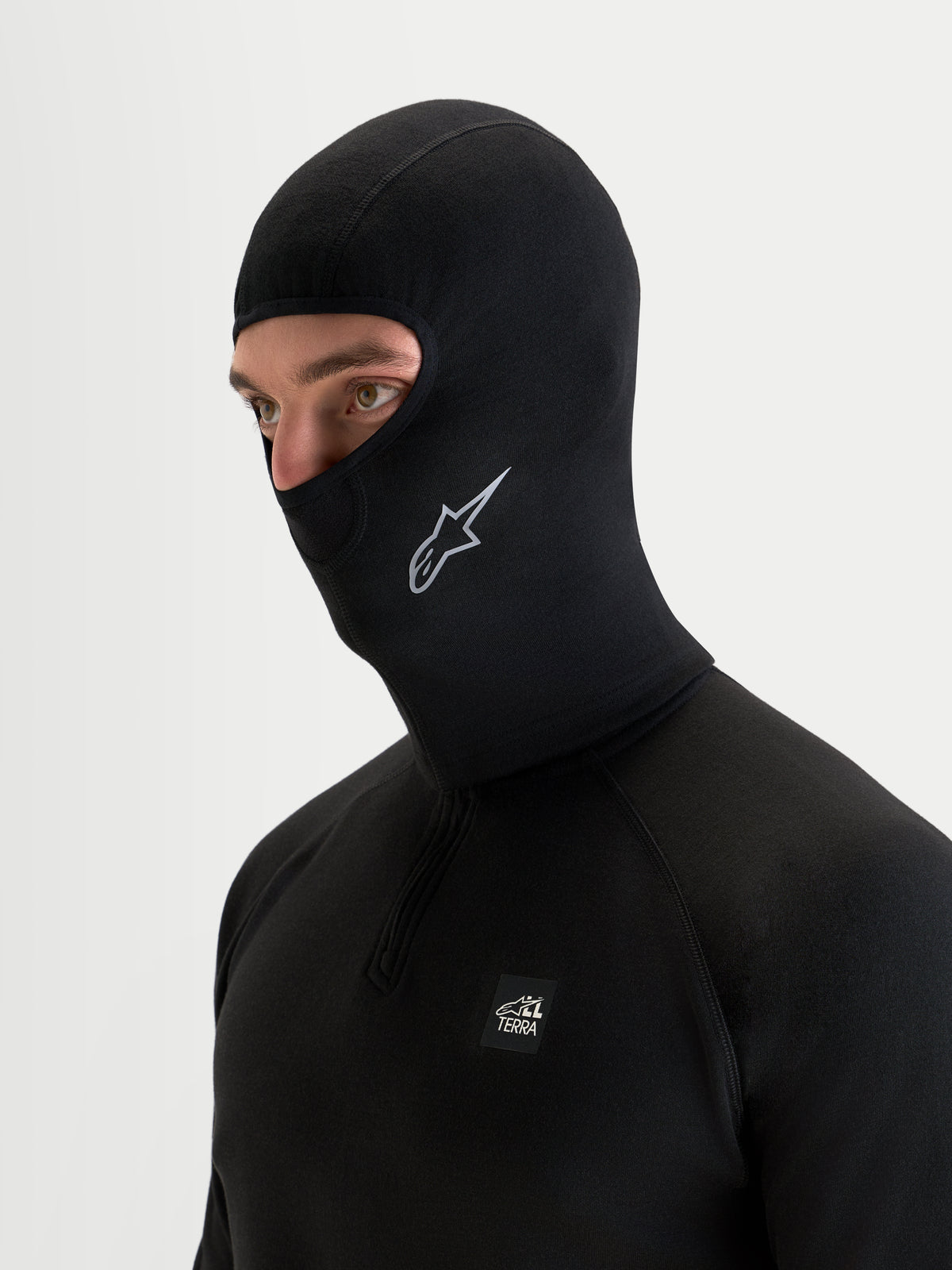 Alpinestars At 8 Merino Balaclava, balaclava de moto térmica em mistura de merino, preta, vista lateral num modelo a mostrar cobertura alargada do pescoço e logótipo Alpinestars