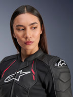 Mulher a usar o Casaco de Couro Alpinestars Stella Dusk em Black Diva Pink White, com logótipo branco no peito, detalhes em rosa vibrante e proteção externa de ombro DFS, equipamento de motociclismo em couro bovino premium
