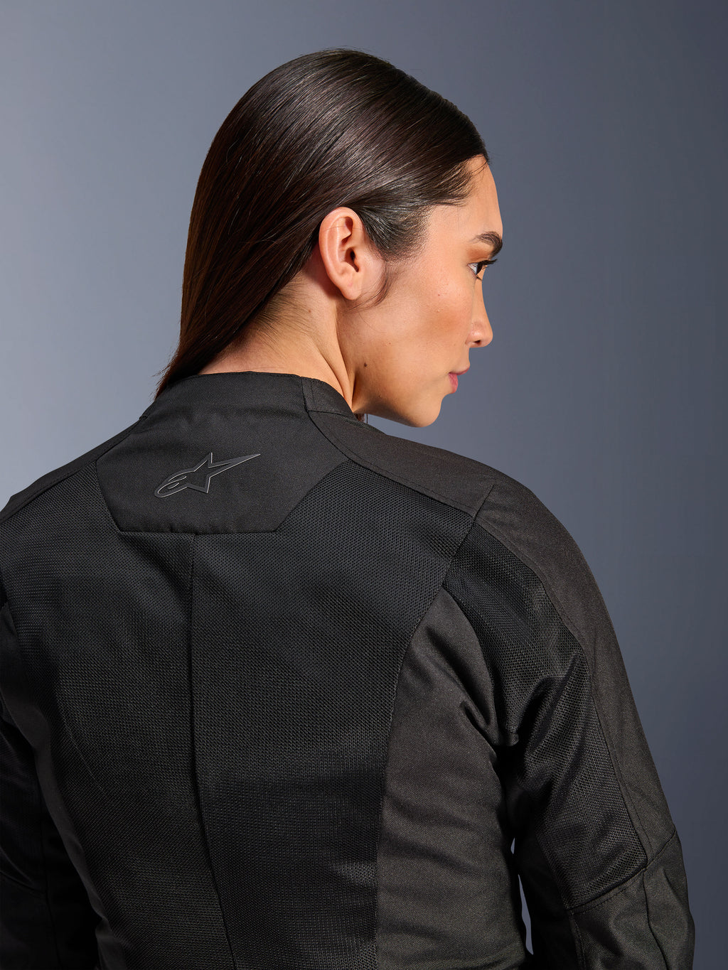 Alpinestars Woman Stella C-1 Air Jacket, Textile Motorcycle Jacket, Black, close-up rear view showing tech mesh ventilation panels and a reflective star logo on the upper back, modern urban riding gear