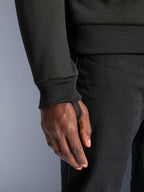 Alpinestars Chrome V2 Sport Hoodie, black tech fleece, close-up of ribbed sleeve cuff with integrated thumb loop for riding stability, urban motorcycle apparel detail