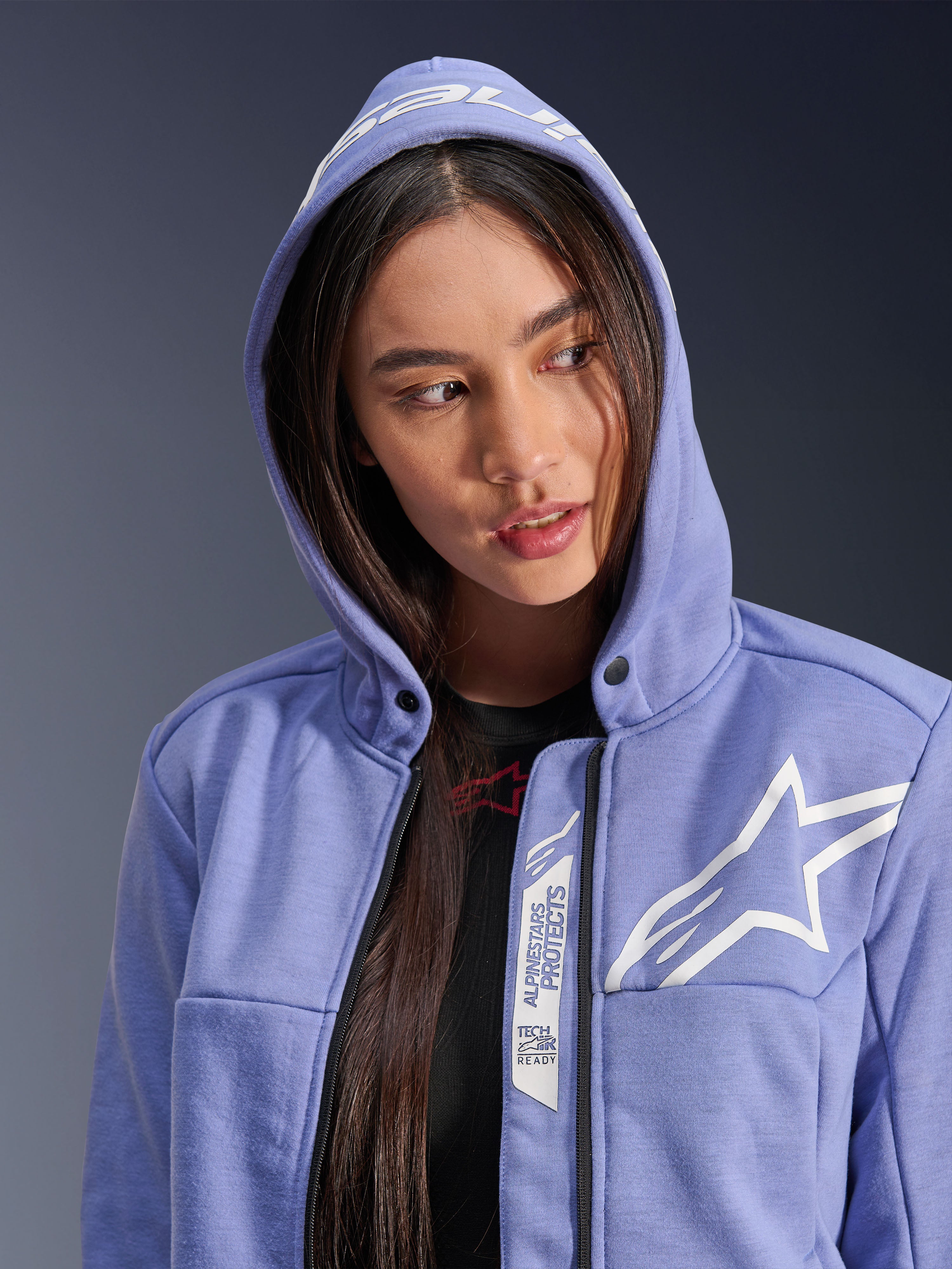 Alpinestars Stella Chrome V2 Sport Hoodie, hoodie de motociclismo para mulher, azul violeta com logótipo de estrela branco, com as marcas 'Alpinestars Protects' e 'Tech-Air Ready' ao longo do fecho, design urbano casual com o capuz colocado.