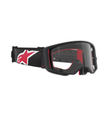 Óculos Alpinestars Supertech Corp, óculos de motocross, pretos, vermelhos e transparentes, vista lateral angular com lente transparente e armação preta, acolchoamento interior vermelho, correia preta com um logótipo Alpinestars grande em vermelho e branco, proteção ocular profissional para off-road
