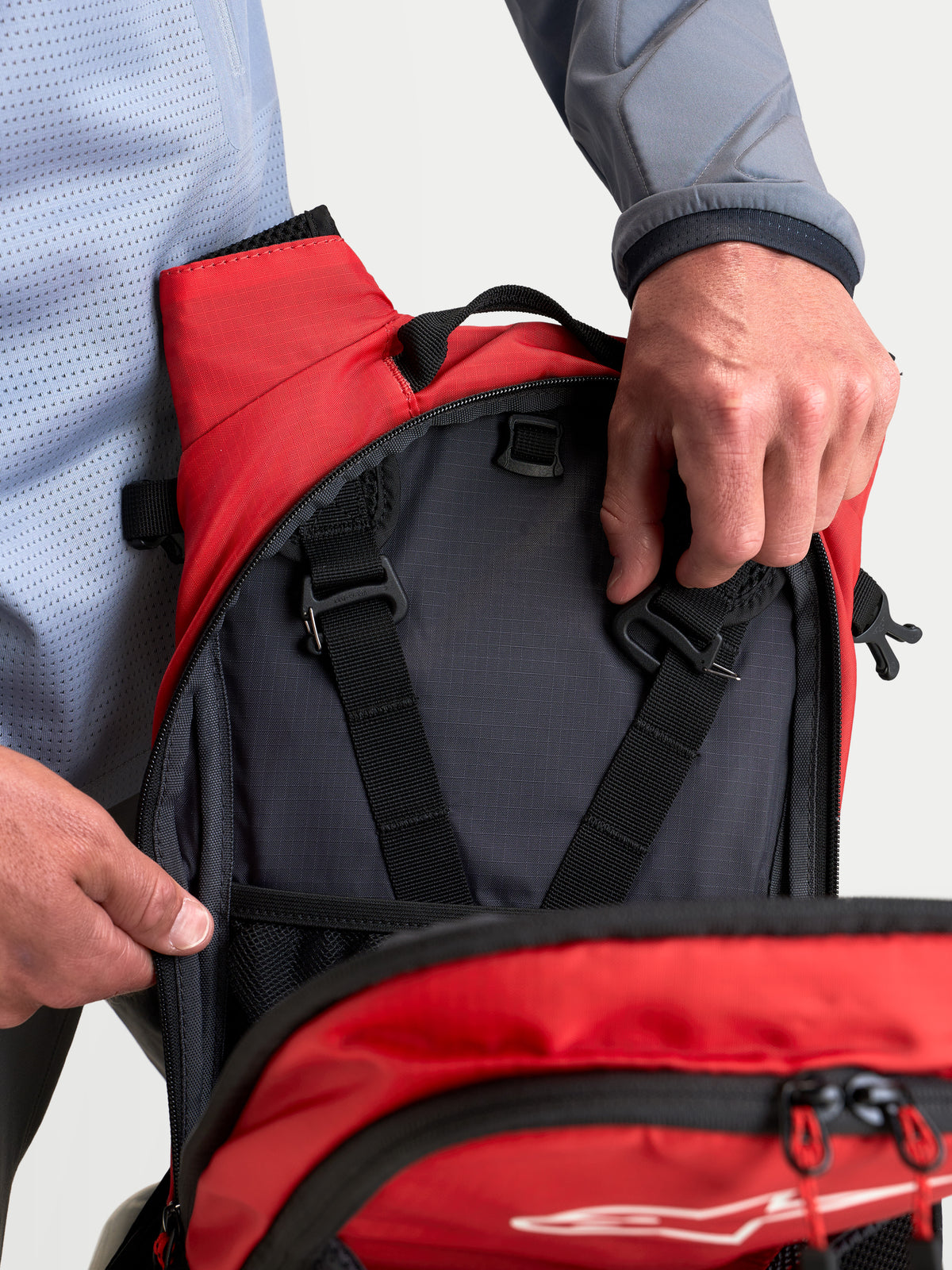 Alpinestars Mochila AT-9, mochila de motocross para o dia a dia, preto e vermelho vivo, vista em plano aproximado dos compartimentos de arrumação interiores e alças de ajuste do arnês