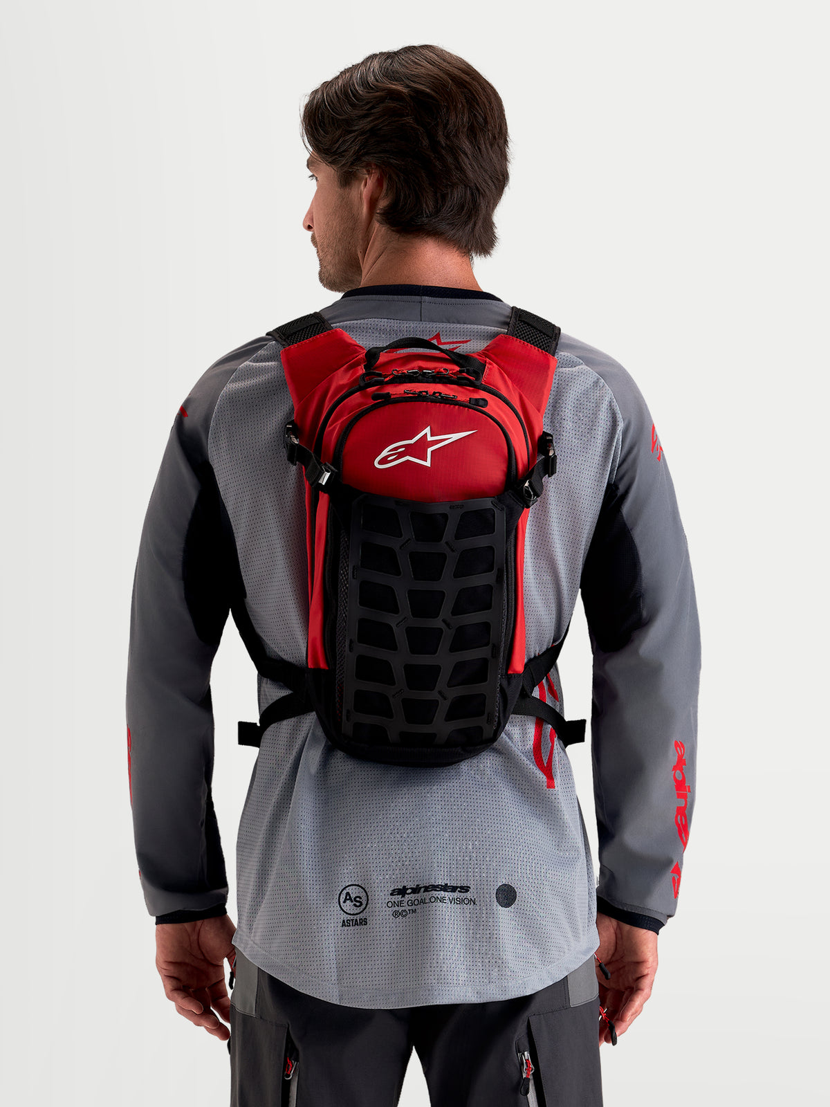 Alpinestars Mochila AT-9, mochila de motocross, preto e vermelho, vista traseira num modelo a mostrar construção têxtil leve e sistema de arnês acolchoado