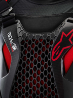 Alpinestars Airbag Tech-Air® Off-Road, pormenor em plano aproximado do sistema de airbag para motociclismo todo-o-terreno, preto e vermelho, com proteção de peito em favo de mel Nucleon CELL, logótipo Tech-Air e estrutura em malha elástica respirável