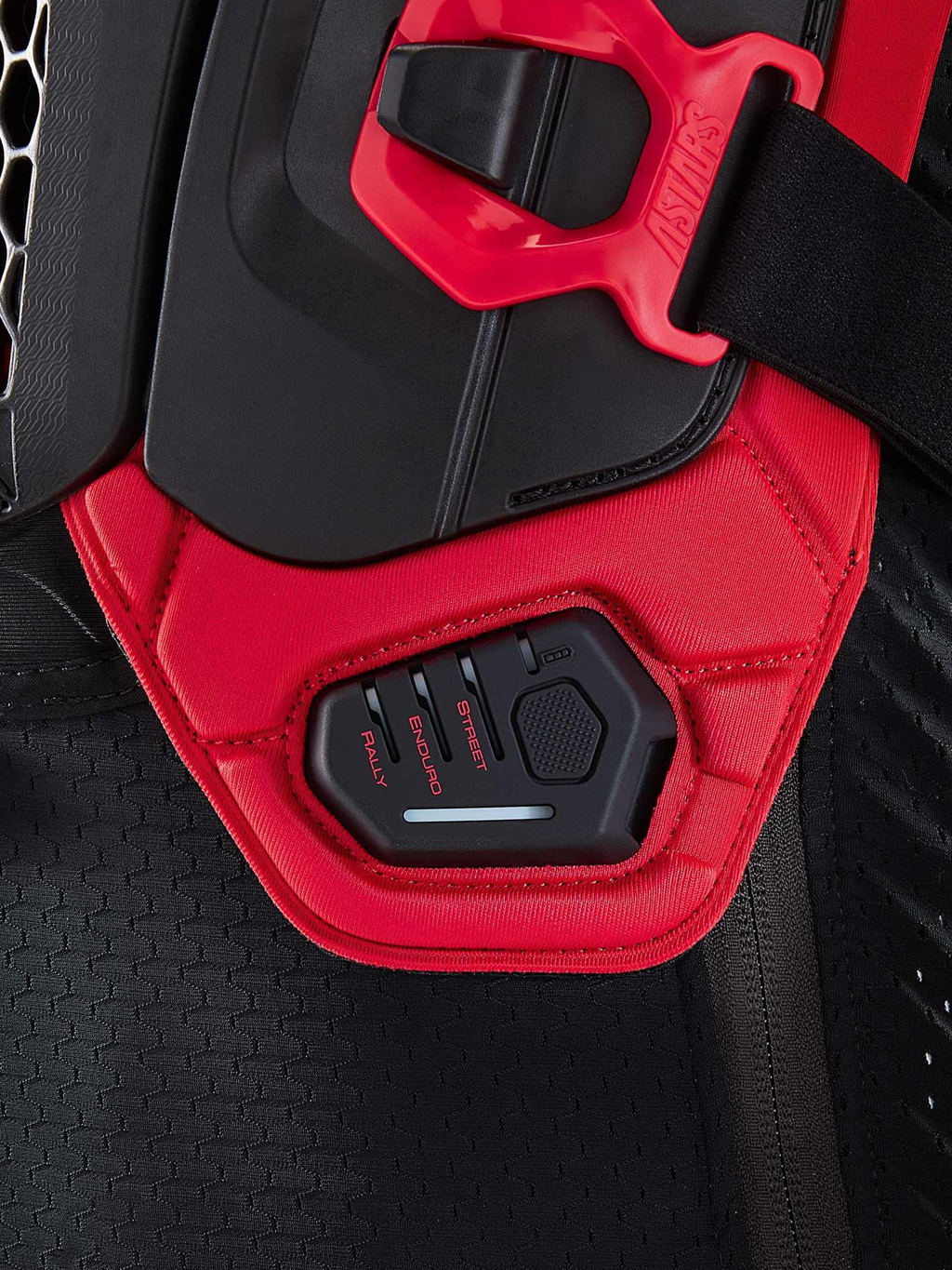 Alpinestars Tech-Air® Off-Road System, pormenor em close-up do airbag de moto todo-o-terreno mostrando o visor da unidade de controlo com os modos de condução RALLY, ENDURO e STREET, preto e vermelho, construção em têxtil