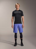 Alpinestars A-Aria Lite Short em Baja Blue, calções de BTT para homem, usados com uma camisola de manga curta preta e joelheiras de proteção, com perfurações a laser para ventilação, equipamento de performance para mountain bike
