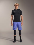 Alpinestars A-Aria Lite Short em Baja Blue, calções de BTT para homem, usados com uma camisola de manga curta preta e joelheiras de proteção, com perfurações a laser para ventilação, equipamento de performance para mountain bike