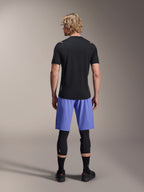 Camisola de Manga Curta Alpinestars A-Aria Switch, camisola de BTT preta, vista de trás, combinada com calções de BTT azuis e proteção de pernas preta, equipamento de ciclismo de performance para trilhos