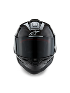 Capacete Alpinestars Supertech R10 Solid, vista frontal, acabamento em carbono preto mate e brilhante, trama de fibra de carbono visível, logótipo Alpinestars branco, viseira fumada escura, capacete de motociclismo de corrida aerodinâmico