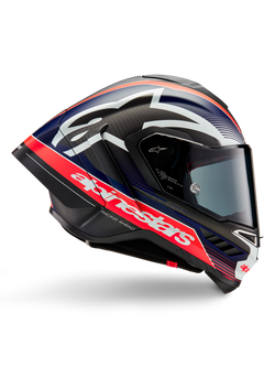 Capacete Alpinestars Supertech R10 Team, capacete de motociclismo de corrida, carbono preto com detalhes em vermelho fluo e azul mate, marca Alpinestars em branco de grandes dimensões, design aerodinâmico com spoilers integrados, viseira transparente, textura de fibra de carbono visível, perfil de corrida elegante