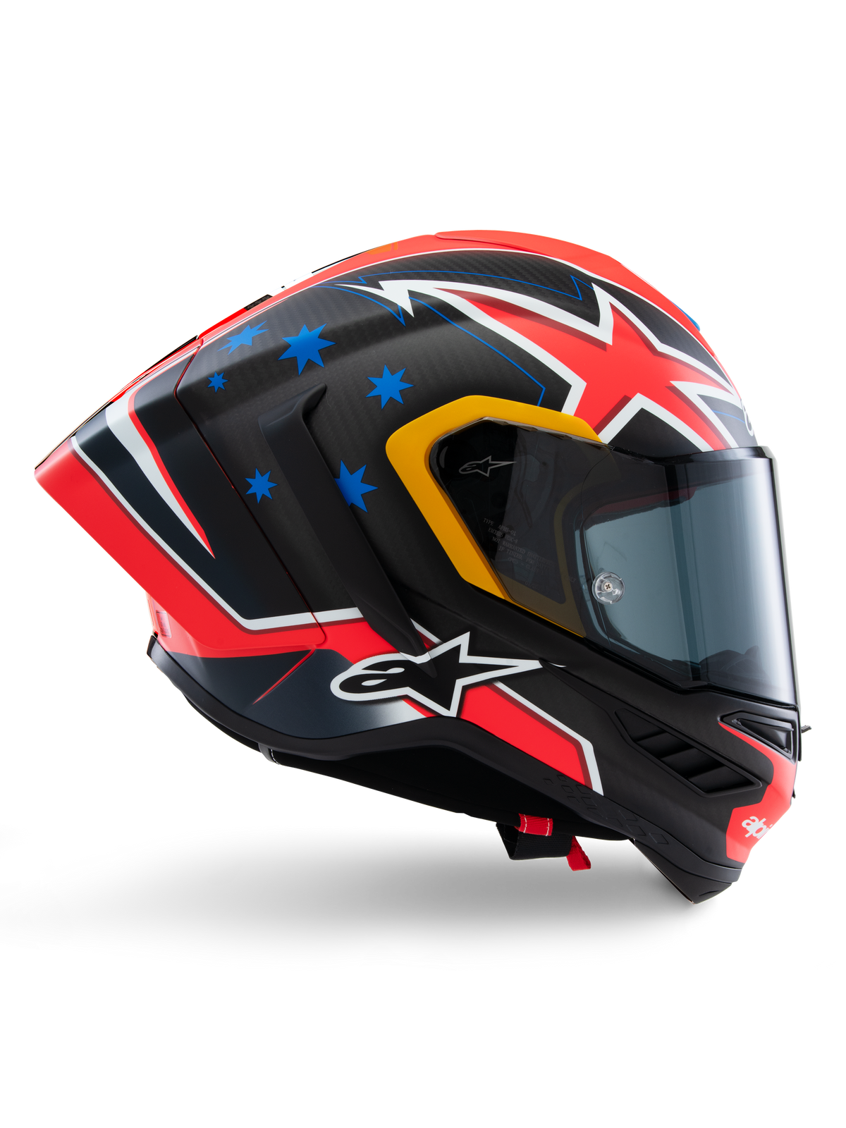 Capacete Alpinestars Supertech R10 Miller Limited Edition, capacete integral de corrida, carbono mate com gráficos vermelhos, brancos e azuis, detalhes de estrelas azuis e acabamento da viseira em amarelo, perfil aerodinâmico com viseira fumada escura, equipamento de segurança de motociclismo de alta performance