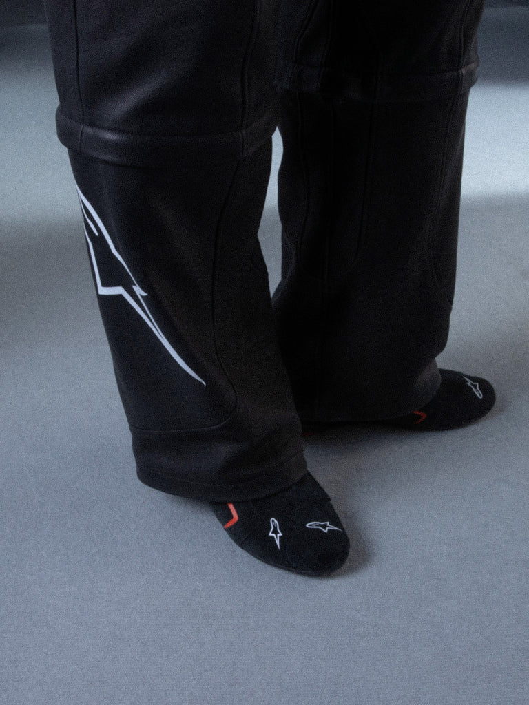 Alpinestars RSRV Starline Shoes, calças pretas com logótipo branco lateral, textura lisa com detalhes de costura, meias pretas com design vermelho e branco