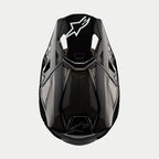 Alpinestars Supertech M10 Solid Helmet, Motocross Helmet, Black Glossy Carbon, Top-down view showing visible carbon fiber weave, white Astars logo on the visor, sleek aerodynamic profile with integrated ventilation ports