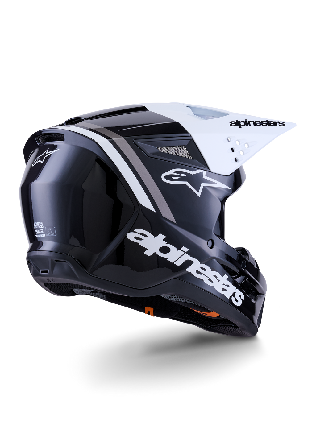 Capacete Alpinestars S-M3 Radium, capacete de motocross, preto, branco e cinzento brilhante, vista lateral traseira com viseira branca, logótipo Alpinestars em destaque na lateral e na traseira, calota aerodinâmica com malha de ventilação, concebido para motocross todo-o-terreno e enduro