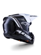 Capacete Alpinestars S-M3 Radium, capacete de motocross, preto, branco e cinzento brilhante, vista lateral traseira com viseira branca, logótipo Alpinestars em destaque na lateral e na traseira, calota aerodinâmica com malha de ventilação, concebido para motocross todo-o-terreno e enduro