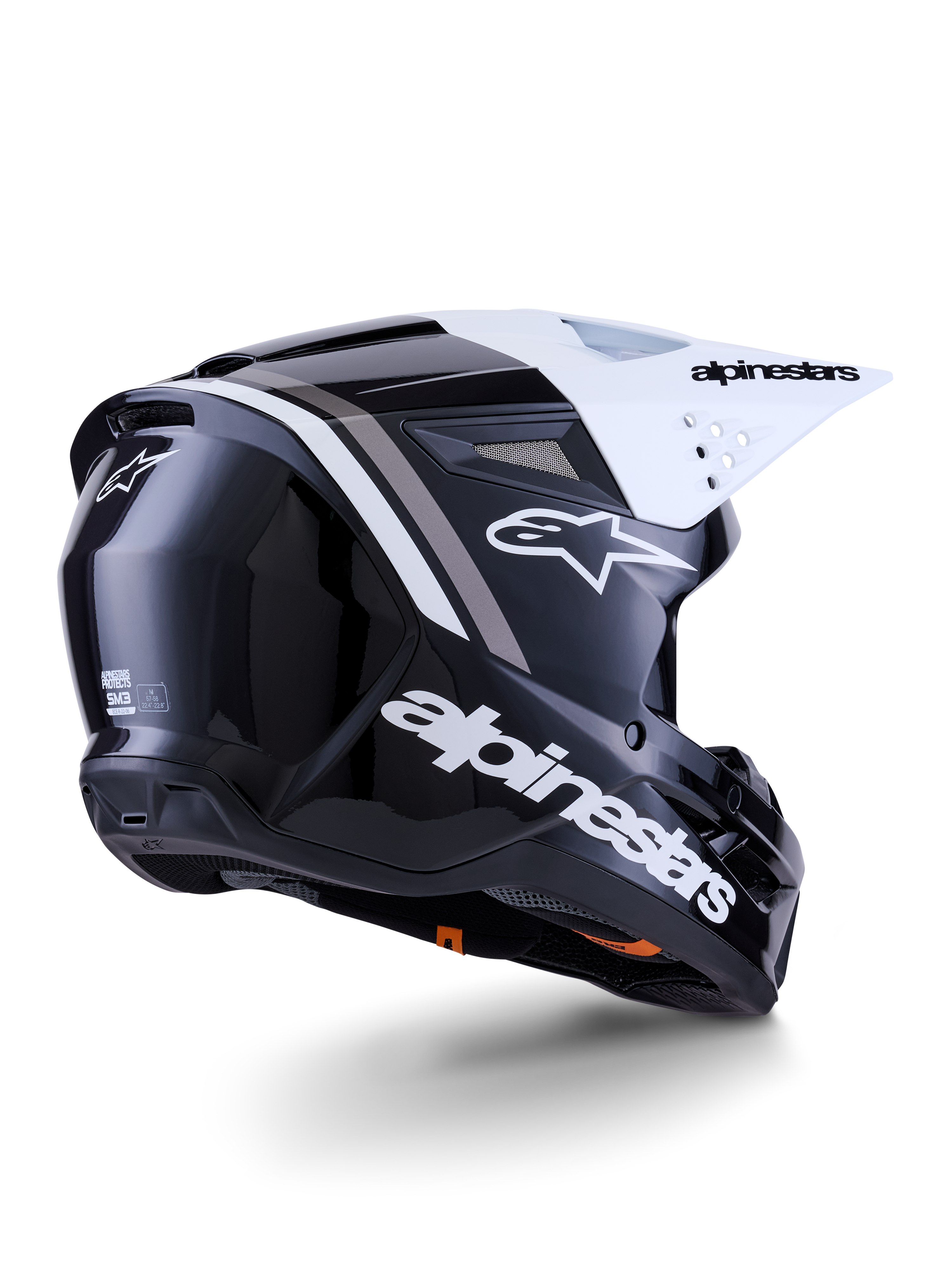 Capacete Alpinestars S-M3 Radium, capacete de motocross, preto, branco e cinzento brilhante, vista lateral traseira com viseira branca, logótipo Alpinestars em destaque na lateral e na traseira, calota aerodinâmica com malha de ventilação, concebido para motocross todo-o-terreno e enduro