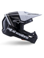 Capacete Alpinestars S-M3 Radium, capacete de motocross off-road, preto, branco e cinzento brilhante, com design aerodinâmico angular e aberturas de ventilação, vista de perfil lateral, acabamento brilhante com riscas cinzentas e viseira branca com logótipo Alpinestars