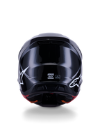Capacete Alpinestars S-M7 Solid ECE 22.06, capacete de motocross, preto brilhante, vista traseira com logótipos de estrela brancos, calota composta aerodinâmica com acabamento de alto brilho, etiquetas de certificação de segurança e de tamanho no centro
