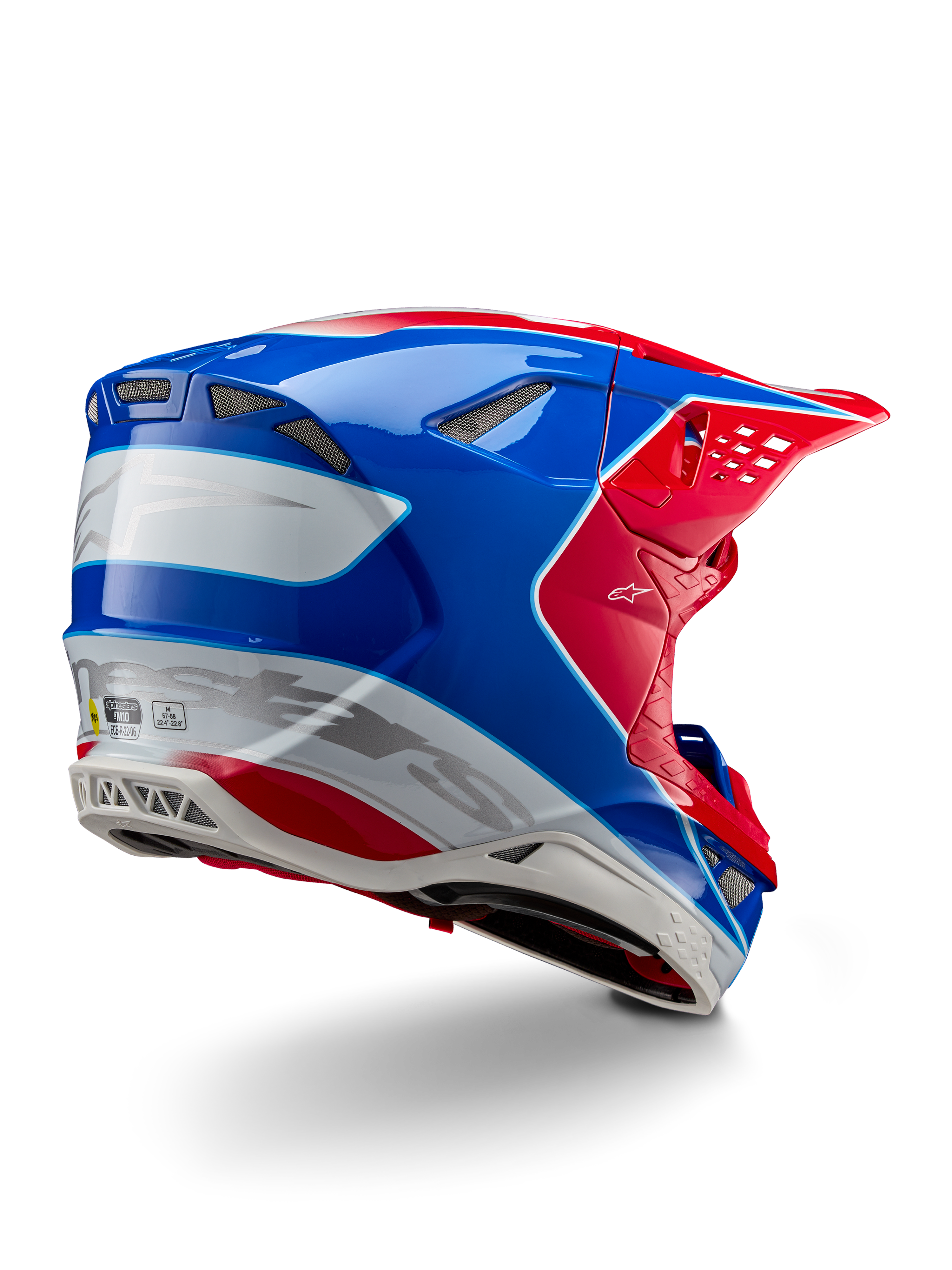 Capacete Alpinestars Supertech M10 Aeon ECE 22.06, capacete de motocross, vermelho brilhante, azul e branco com acabamento brilhante, vista lateral traseira com perfil aerodinâmico, logótipo Alpinestars prateado e aberturas de ventilação integradas.