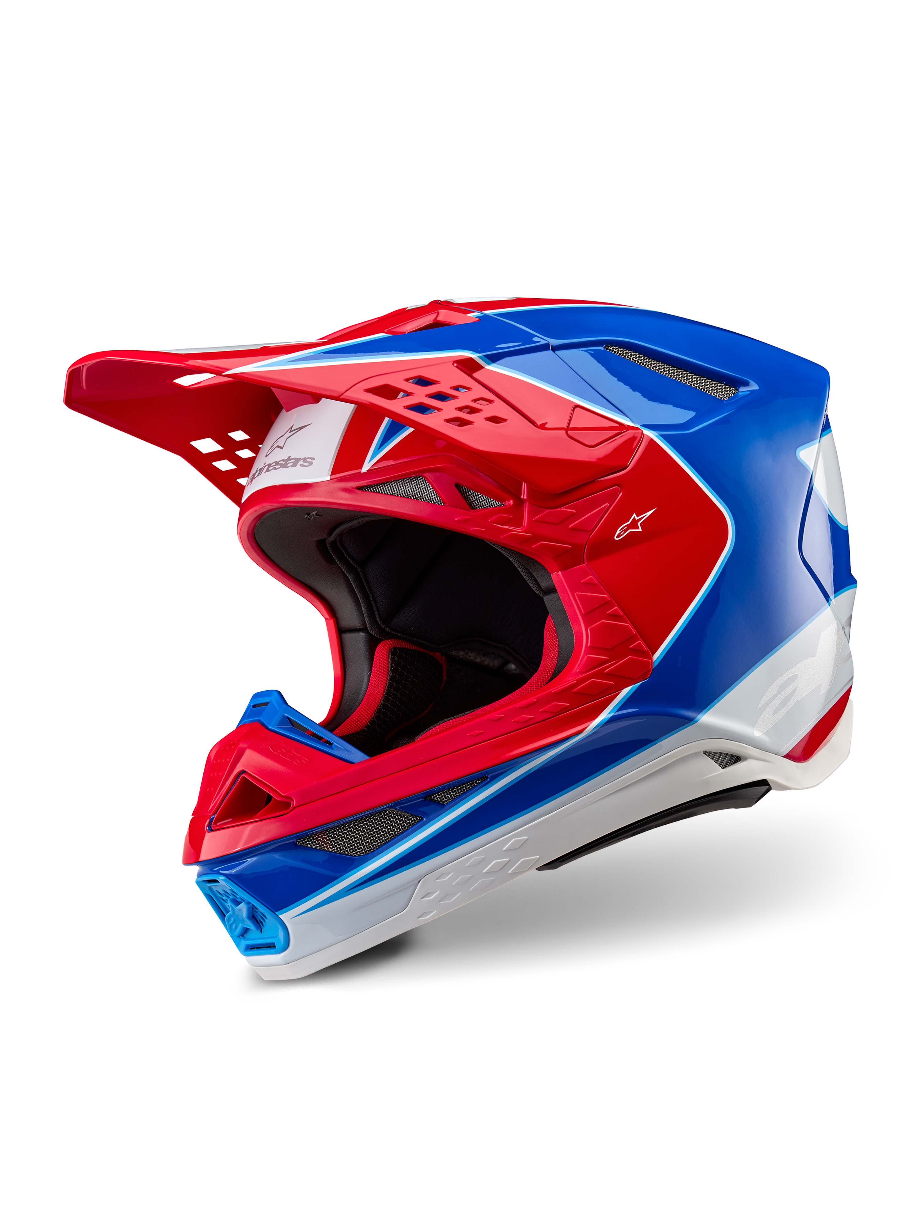 Capacete Alpinestars Supertech M10 Aeon, capacete de motocross, vermelho e azul brilhante, vista em três quartos mostrando a calota aerodinâmica com múltiplas aberturas de ventilação, pormenores gráficos em branco e vermelho, logótipo Alpinestars na viseira e na lateral, equipamento de corrida profissional todo-o-terreno