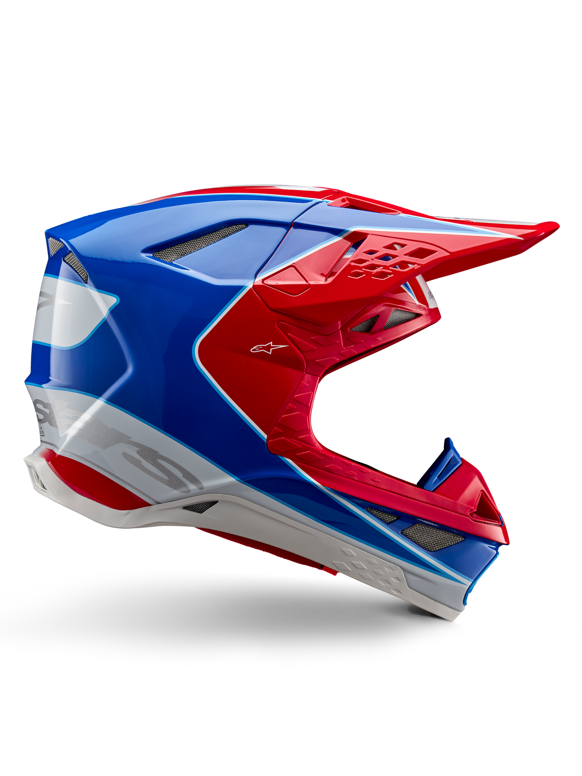 Capacete Alpinestars Supertech M10 Aeon, capacete de corrida de motocross, vermelho vivo, azul e branco, acabamento brilhante, perfil lateral aerodinâmico com múltiplas aberturas de ventilação cobertas por malha, contornos angulares e pala