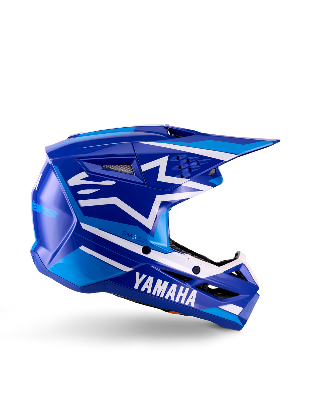 Capacete de Motocross para Jovens Yamaha S-M3, azul e branco brilhante, vista de perfil lateral com marca Yamaha em destaque e logótipo de estrela da Alpinestars, design geométrico com realces em azul claro, calota ventilada com viseira longa, proteção de cabeça para todo-o-terreno com certificação ECE 22.06